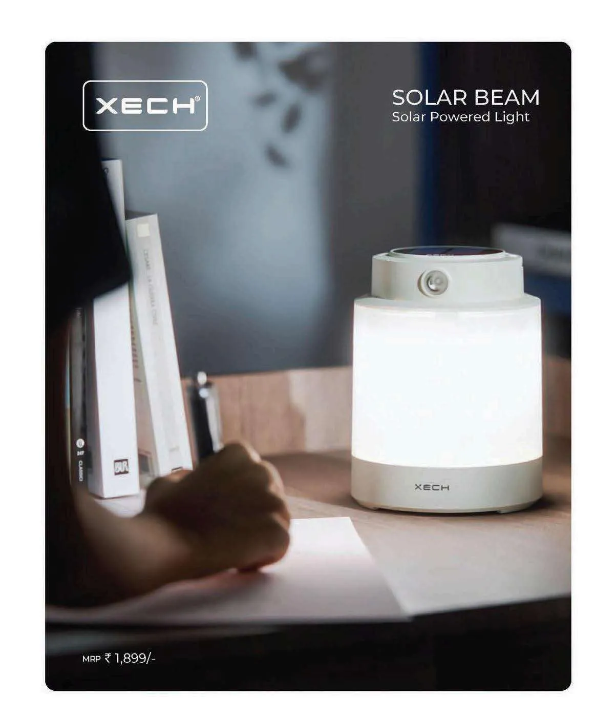 White XECH Beam Plus lantern lamp with a glowing shade and a top hook, glowing warmly on a desk beside books.