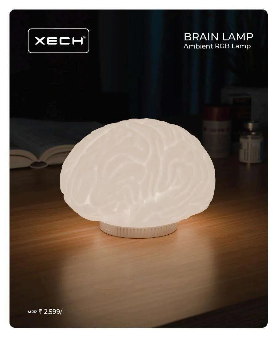 White brain-shaped XECH ambient RGB lamp glowing on a wooden desk in a dim room