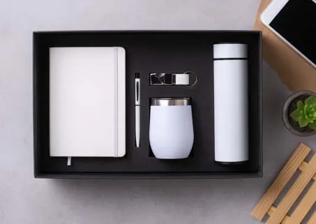 White five-piece gift set with diary, pen, keychain, stemless tumbler and temperature-display flask in a black tray.
