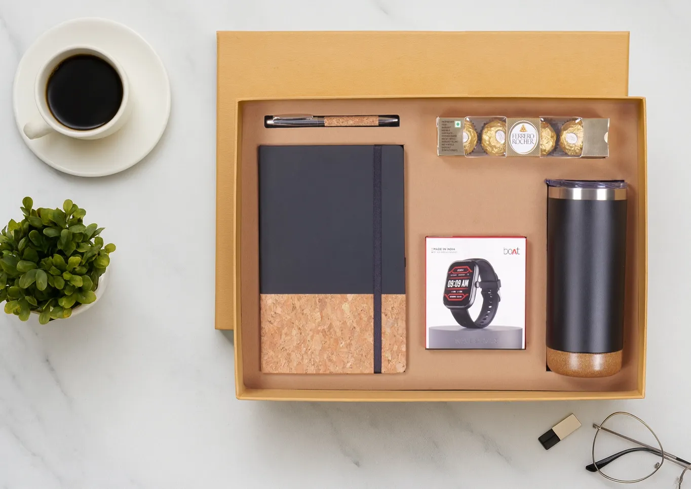Open kraft gift box with cork-and-black diary, cork pen, boxed boAt smartwatch, black insulated tumbler and Ferrero Rocher chocolates.
