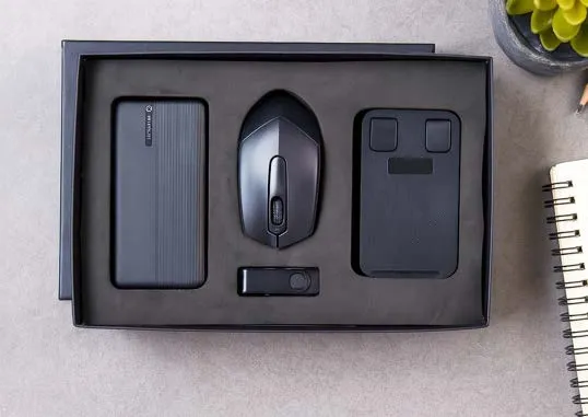 Black gift box with power bank, wireless mouse, USB drive and a slim case in foam tray.