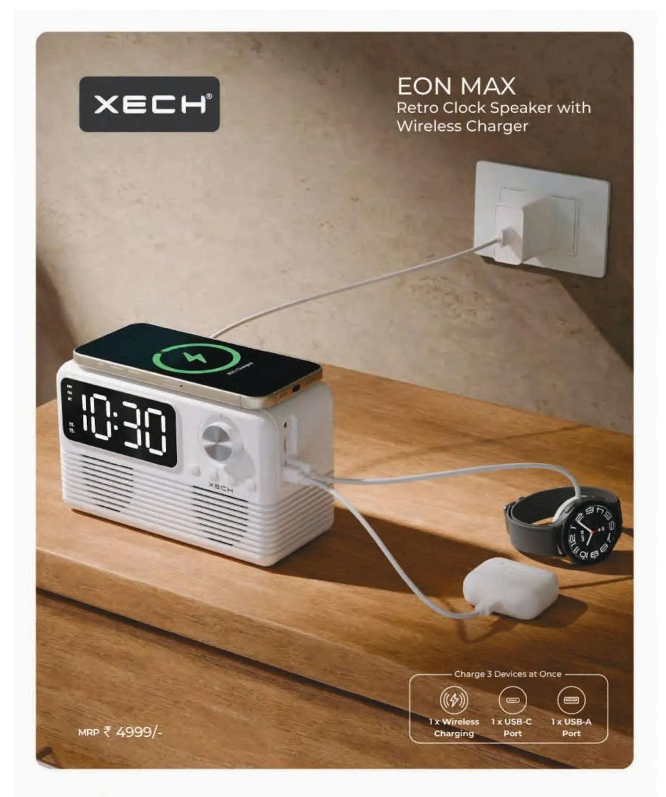 White retro XECH Eon Max clock speaker charging a phone wirelessly on its top pad with watch and earbuds nearby on a wooden table.