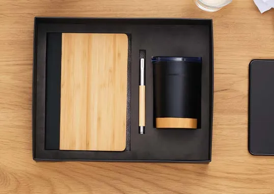 Black gift tray holding a bamboo-cover diary, a slim pen and a black tumbler with bamboo base