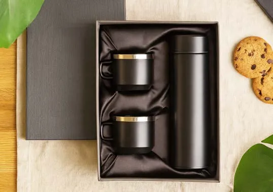 Matte black vacuum flask and two gold-rimmed mugs in a satin-lined gift box