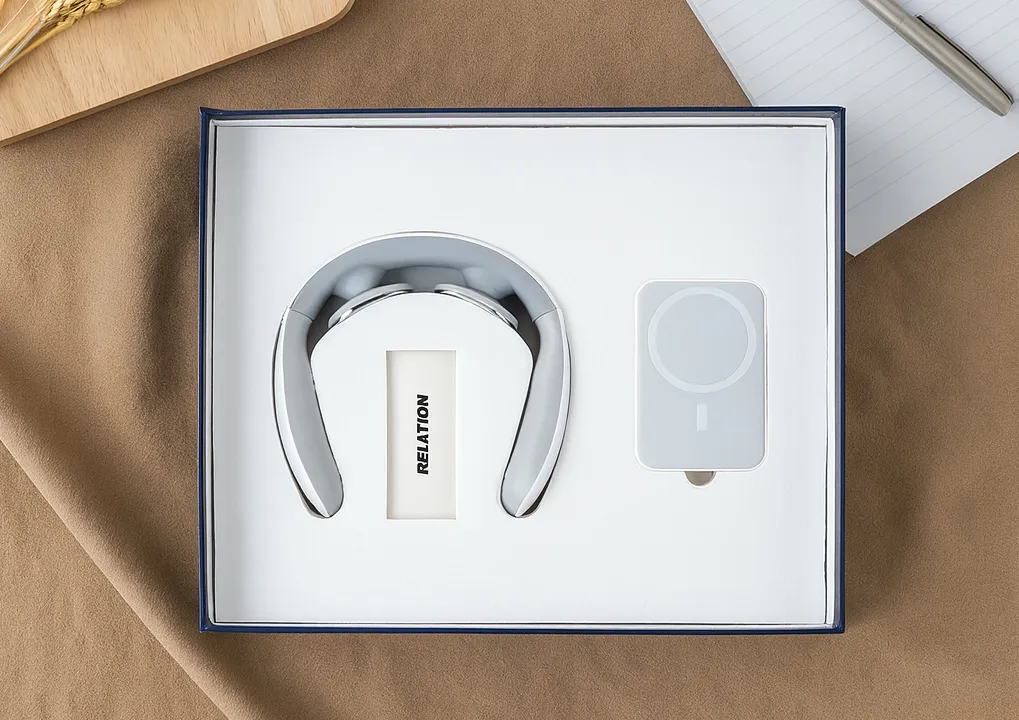 Open navy-trimmed gift box holding a chrome U-shaped neck massager and a white magnetic wireless power bank.