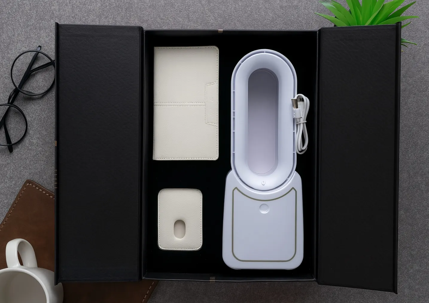 Open black gift box containing a white bladeless tower fan, ivory leatherette diary and a white desktop unit with USB cable.