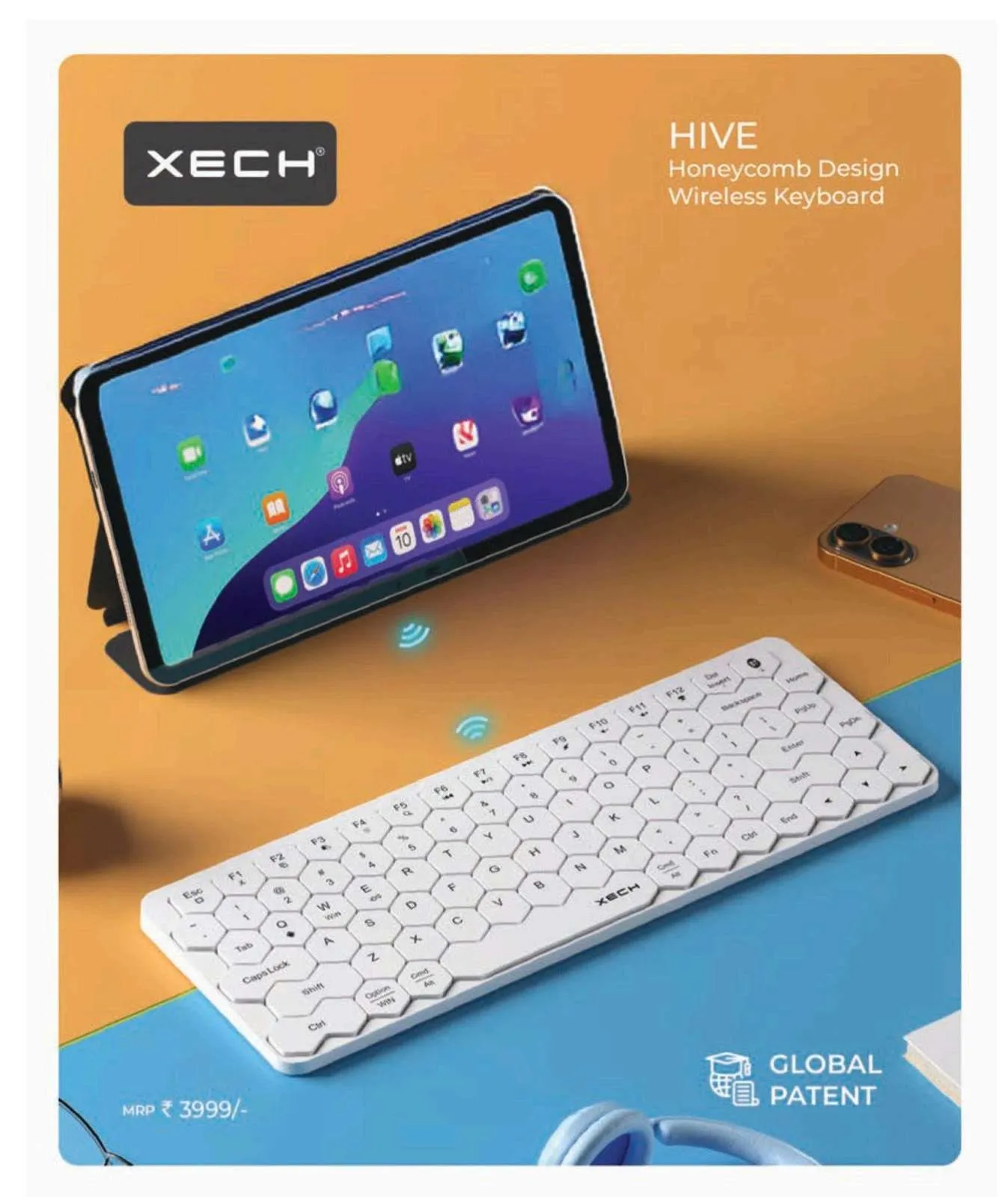Slim white XECH Hive wireless keyboard with hexagonal honeycomb keys on an orange and blue surface beside a propped-up tablet.