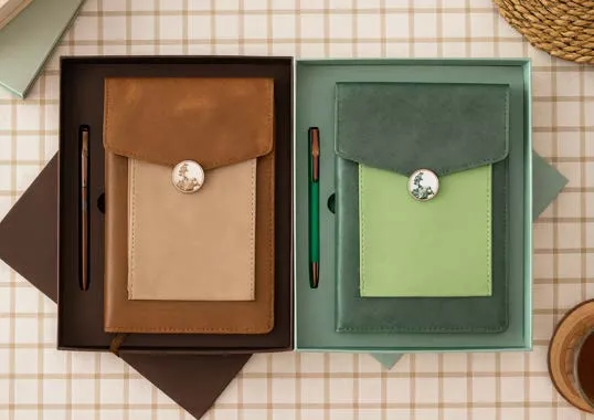 Brown and green leatherette flap diaries with matching pens in open gift boxes