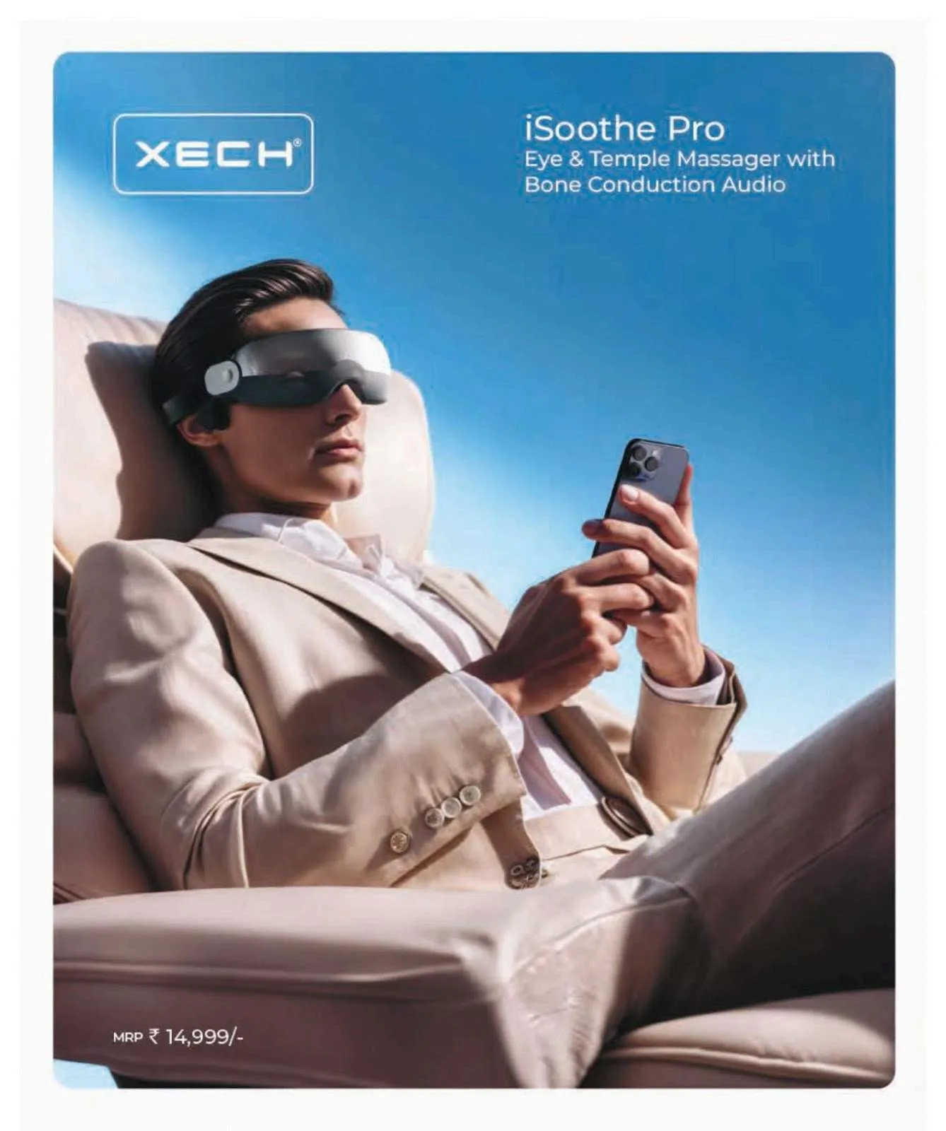 Man in a beige suit reclining and using a phone while wearing a grey XECH iSoothe Pro eye and temple massager visor.
