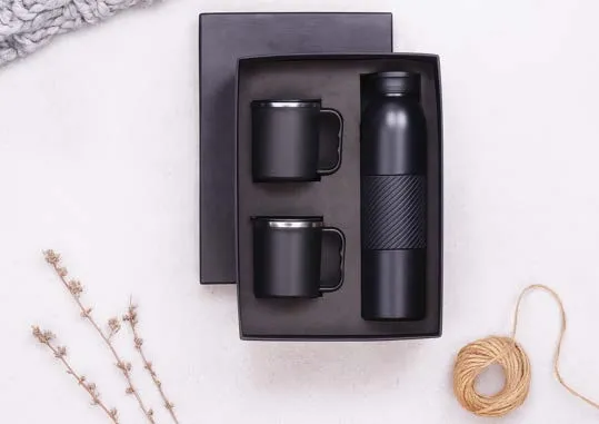 Gift box with two black steel mugs and a ribbed black insulated flask.