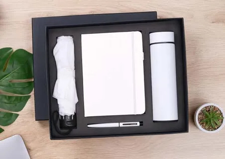 Black gift box holding a white folding umbrella, white A5 diary, white flask and white pen.