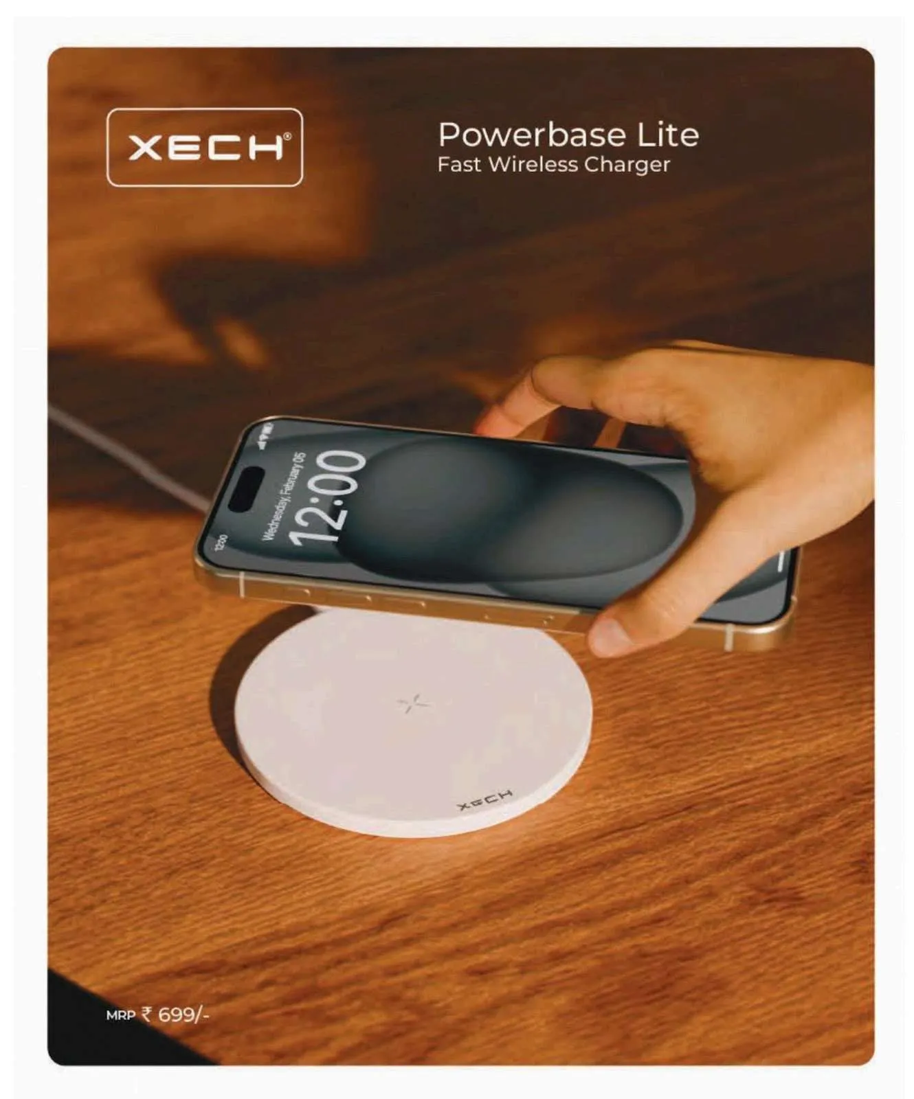 White round XECH Powerbase Lite wireless charging pad on a wooden desk with a phone held just above it.