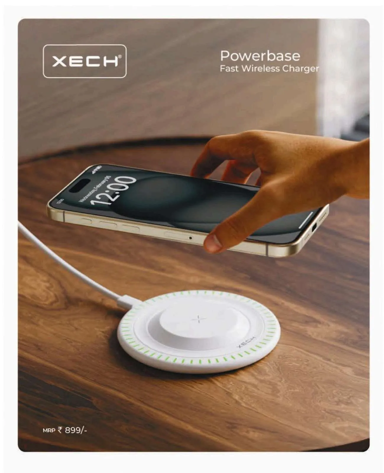 White round XECH Powerbase wireless charging pad with a green LED ring on a wooden table, a phone held above it.