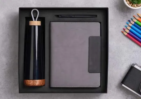 Black wood-base bottle, grey leatherette diary and pen arranged in a black gift tray