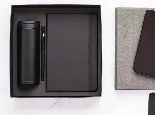 Black insulated flask, black hardbound diary and black pen arranged in a fitted black gift box.