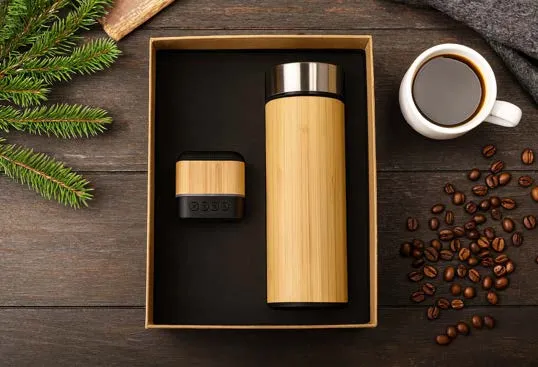 Bamboo flask and small bamboo-finish speaker set in a kraft gift box on a dark wood table
